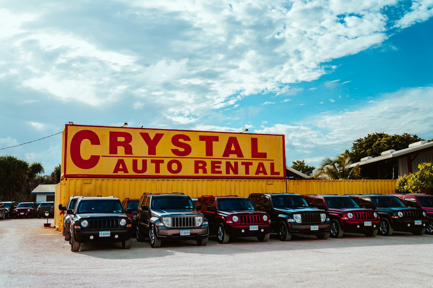 Crystal Auto Rental sign above parked SUVs on a gravel lot.