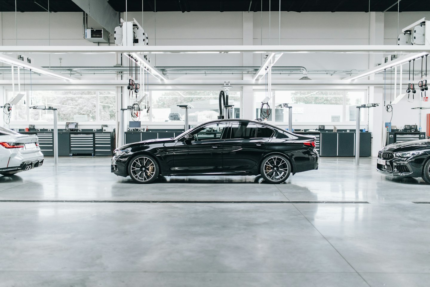 Three luxury cars in a modern service bay.